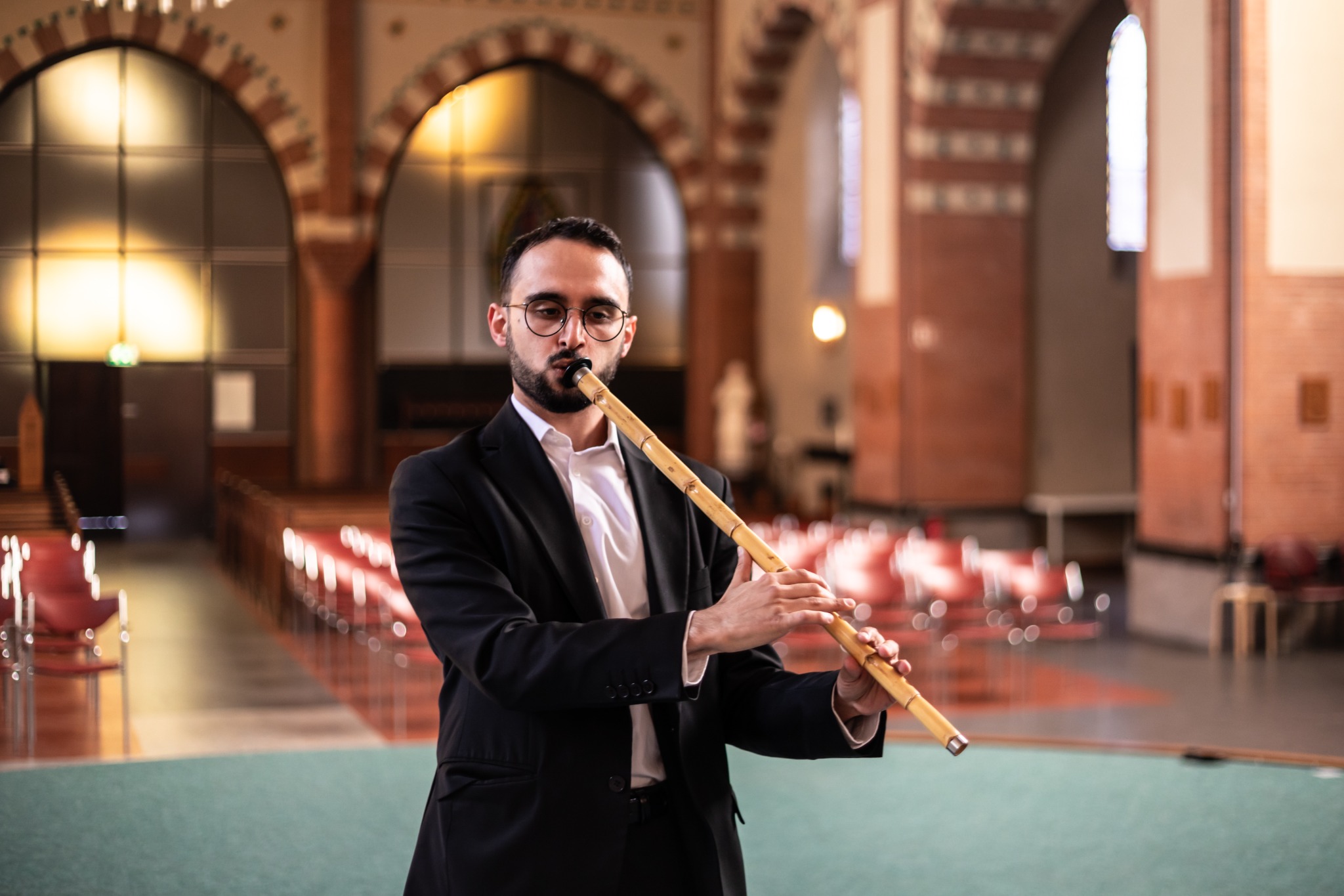 Şükrü Kirtiş performing on the ney in a vaulted concert hall